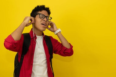 Profilde, kahverengi tenli genç bir adam şarkı söylerken telli kulaklıklı, kırmızı resmi giyinmiş ve sarı arka planda gözlüklü, reklam metinleri için yeri olan bir müzik dinliyor.