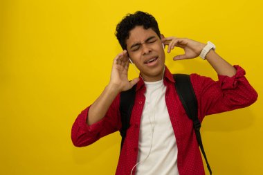 Genç koyu tenli Latin bir adamın telli kulaklıklarla müzik dinlerken şarkı söylemesini ön planda tutmak. Sarı bir elbise ve reklam metinleri için yeri olan kırmızı bir elbise.