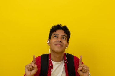 Gülümseyen kahverengi tenli, kırmızı günlük kıyafetler giyen Latin bir öğrenci sarı arka plandaki yazı için ellerini havaya kaldırarak işaret ediyor. Reklam için telif alanı olan grafik kaynağı.