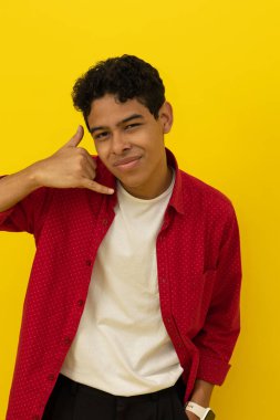 Koyu tenli, kırmızı elbiseli, neşeli, genç bir Latin 'in dikey görüntüsü. Elleri sarı arka planda, fotokopi alanı olan bir jest yapıyor.