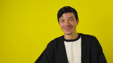Bıyıklı genç, çilli bir adam gülümsüyor ve reklam için fotokopi alanı olan sarı bir arka plana işaret veriyor.