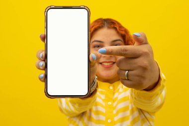 Cep telefonunun boş ekranını gösteren neşeli, genç, kızıl saçlı bir kadının yakın plan fotoğrafını çek.