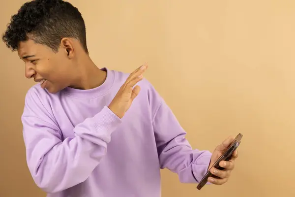 Dehşete düşmüş, koyu tenli, tiksindirici bir yüzü olan Latin adam cep telefonuna bakmamak için yüzünü çeviriyor.