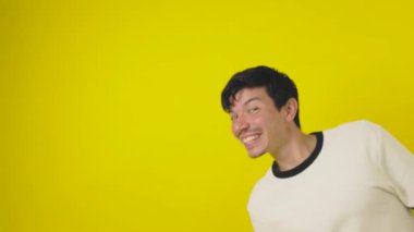 Neşeli çilli genç adam yan taraftan beliriyor. Eli sarı bir arka planda, telif boşluğunda selamlaşıyor.