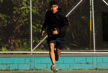 Genç Latin bir adam sabah parkta düz bir çizgide hızlı koşuyor yarış yapıyor, sağlıklı bir yaşam tarzı.