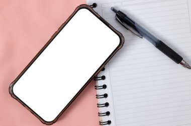 Pembe arka plan, organizasyon ve iş planlama kavramına sahip bir defter ve kalem üzerinden akıllı telefonun genel görünümü