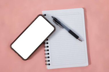 Pembe arka plan, organizasyon ve iş planlama kavramına sahip bir defter ve kalem üzerinden akıllı telefonun genel görünümü
