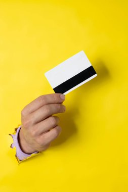 Elinde bir banka kartı olan yırtık bir kağıt delikten çıkan erkek el, fotokopi alanı olan alışveriş kavramı