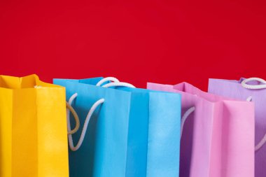 Kırmızı arka plan, alışveriş ve tüketim kavramında çok renkli alışveriş torbaları bir arada