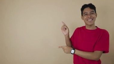 Kırmızı tişörtlü gülümseyen Latin bir adam açık kahverengi arka plan, reklam ve tanıtım kavramının fotokopi alanını gösteriyor.