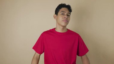 Koyu tenli Latin bir adam açık kahverengi bir arka planda inkar jesti olarak kollarını kavuşturuyor. Reddedilme, anlaşmazlık ve onaylanmama kavramı