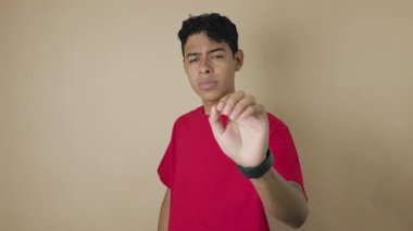 Kırmızı gömlekli genç Latin bir adam avucunu uzatıp açık kahverengi bir arka planda kafasını sallarken dur işareti yapıyor. Reddetme, uyarı ve anlaşmazlık kavramı