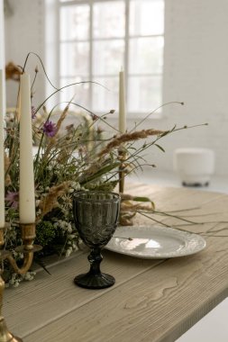 Çiçeklerle süslenmiş bir masanın üzerinde güzel düzenlenmiş fincanların dikey hâli.