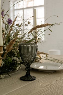 Çiçeklerle süslenmiş bir masanın üzerinde güzel düzenlenmiş fincanların dikey hâli.