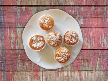 Tahta arka planda şeker tozlu kekler