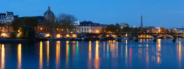 Reflection of Paris city in Seine river with Arts bridge foreground during twilight, Paris, France