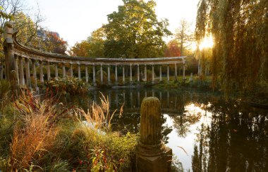 Parc Monceau 'nun antik sütunları sonbaharda oval havzanın suyuna, güneşe yansıyor. Bu halk bahçesi Paris 'in 8. bölgesinde yer almaktadır.