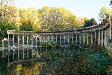 Parc Monceau 'nun antik sütunları sonbaharda oval havzanın suyuna, güneşe yansıyor. Bu halk bahçesi Paris 'in 8. bölgesinde yer almaktadır.