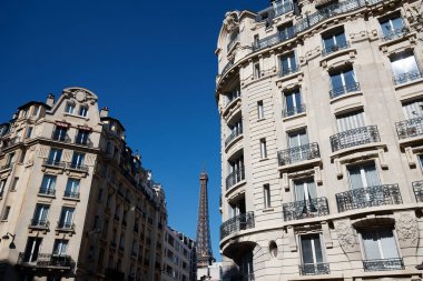 Tipik balkonları, pencereleri ve arka planında Eyfel kulesi olan geleneksel Fransız evleri. Paris, Fransa.