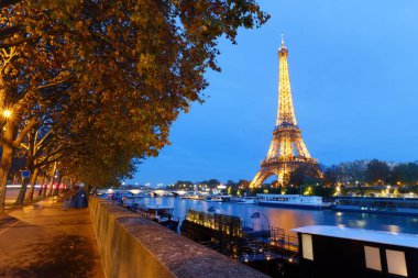 Paris, Fransa-11 Kasım 2023: Eyfel Kulesi 'nin gece manzarası, Seine Nehri' nin bord 'unda gün batımında parlayan ünlü anıt.