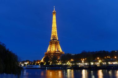 Paris, Fransa-11 Kasım 2023: Eyfel Kulesi 'nin gece manzarası, Seine Nehri' nin bord 'unda gün batımında parlayan ünlü anıt.