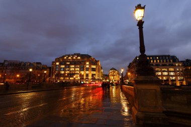 Paris at rainy night cityscape. The view from Pont Neuf bridge.