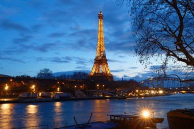 Paris, Fransa-11 Kasım 2023: Eyfel Kulesi 'nin gece manzarası, Seine Nehri' nin bord 'unda gün batımında parlayan ünlü anıt.