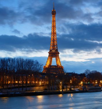 Paris, Fransa-11 Kasım 2023: Eyfel Kulesi 'nin gece manzarası, Seine Nehri' nin bord 'unda gün batımında parlayan ünlü anıt.