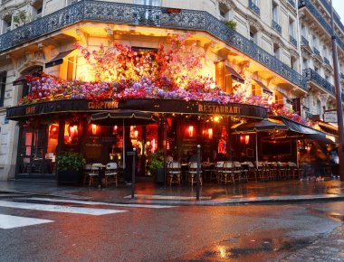 PARIS, FRANCE - 02 Mart 2024: Yağmurlu sabahlarda çiçeklerle süslenmiş klasik Paris Kafe Comptoir manzarası. Ünlü Zafer Kemeri 'nin yakınında yer alıyor..