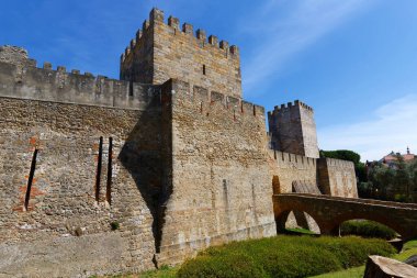 11. yüzyılın yüksek taş duvarlı savunma duvarının bir parçası. Küçük kemerli köprüsü ile kalenin girişine doğru yükselen tepedeki Berberi Aziz George kalesi. Lizbon, Portekiz