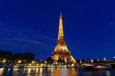 Paris, Fransa-22 Haziran 2024: Paris 2024 Olimpiyat Oyunları 'nın olimpiyat yüzükleriyle Eyfel kulesinin gece manzarası. Paris 'in 7. bölgesinde dünyanın en çok ziyaret edilen anıtıdır..