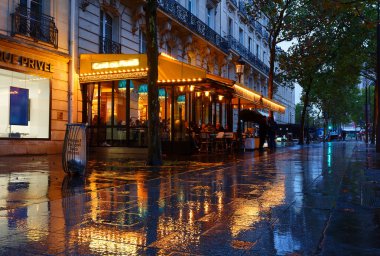 Paris, Fransa - 25 Eylül 2024: yağmurlu bir akşamda geleneksel Fransız Cafe de Paris. Paris 'te Zafer Kemeri yakınlarında yer alıyor. .