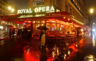 Paris, Fransa - 09 Ekim 2024: yağmurlu gecelerde kimliği belirsiz müşterileri olan geleneksel Fransız cafe brasserie Royal Opera. Fransa 'nın başkenti Paris' teki Ulusal Opera binasının yakınında yer almaktadır..