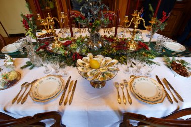 Noel ya da yeni yıl sofrasında mumlar, istiridyeler, gümüş çatal bıçaklar, köknar dallarının süslemeleri