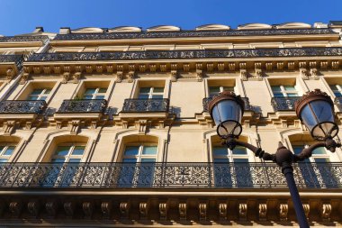 Paris 'te tipik balkonları ve pencereleri olan geleneksel Fransız evinin dış mimarisi. Ön planda geleneksel Paris sokak lambası.