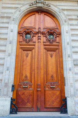 The rich decor decorates an entrance door of the old building of traditional architecture of in downtown, Paris, France.