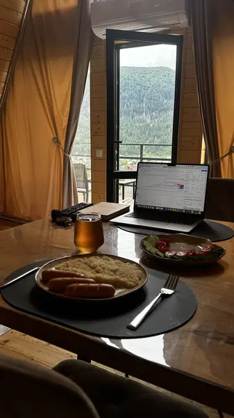 Mutfaktaki masada bir fincan kahve ve dizüstü bilgisayar var.