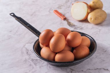 Eggs in a pan ready to beat with a fork and make potato and onion omelette