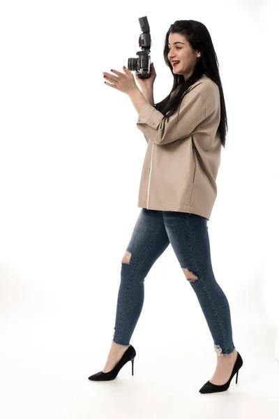 stock image woman photographer taking photos in studio on white background, wearing jeans and brown leather jacket. photo camera session