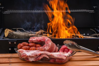 Sosis, tavuk budu, domuz pastırması, domuz kaburgası, sosis ve sebzelerle birlikte açık havada ızgarada kızartılmış et, odun ateşi ve mangal kömürü, duman..