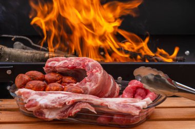 Sosis, tavuk budu, domuz pastırması, domuz kaburgası, sosis ve sebzelerle birlikte açık havada ızgarada kızartılmış et, odun ateşi ve mangal kömürü, duman..
