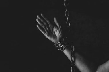 Stüdyoda siyah arka planda zincire vurulmuş bir insan eli, özgürlük eksikliği, hapis