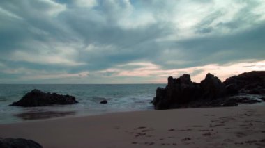 Okyanus kıyısında kayalıklar arasında küçük kumlu bir sahil..