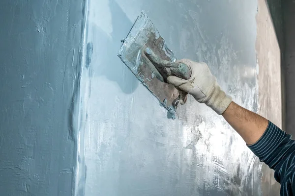 manual work with a trowel for waterproofing the wall.