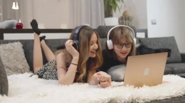 girls rejoice at success, looking at laptop at home on couch. 