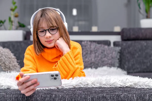 child with smartphone on sofa, home online education. High quality photo