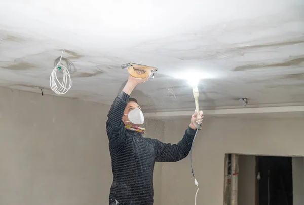 stock image hand sanding of the plasterboard ceiling with a trowel. 