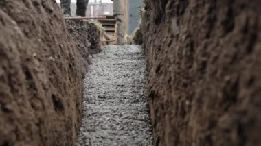 Yerdeki bir kazıya beton dökülüyor. Yeni binanın temelinin somutlaştırılması. 