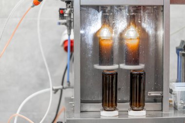 Bira fabrikasındaki bira şişelerini otomatik dolduran bir makine. Yüksek kalite fotoğraf