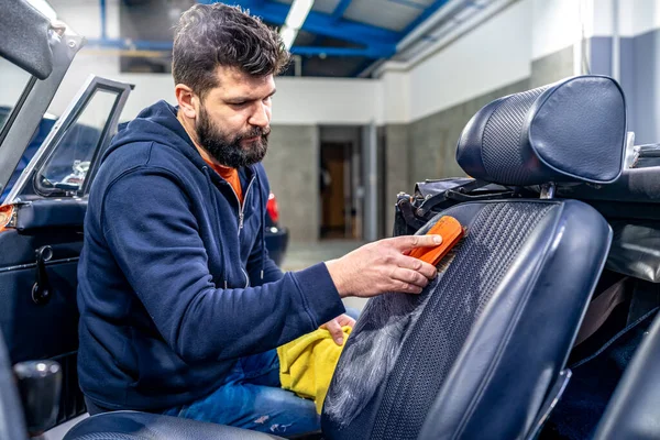 stock image cleaning leather car seats with a brush and chemicals. 